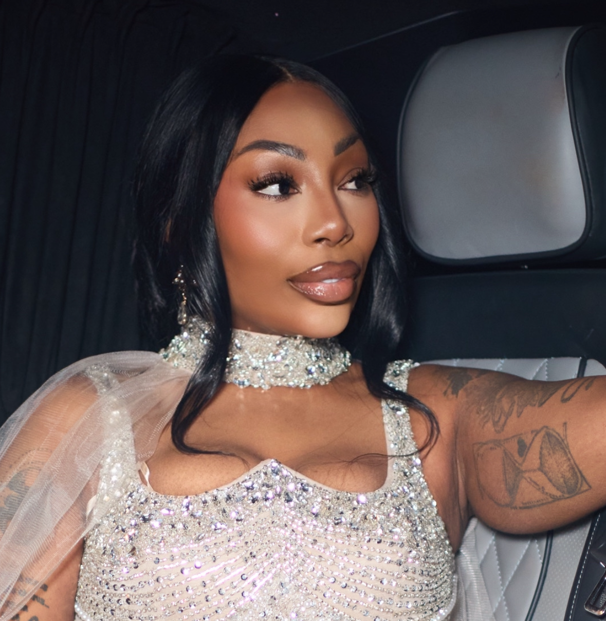 MS ELDE LORDE sparkly dress sitting inside a vehicle with a starry sky background